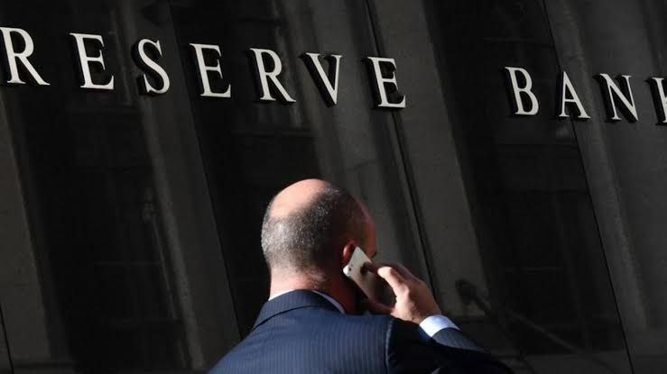 A man stands outside the Reserve Bank, reflecting the disconnect between economic decisions and everyday workers.